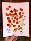 Art print of colorful cherry tomatoes, being held for scale.