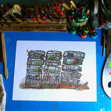 Large colorful print of stacked crab pots, on the artist's desk with art supplies.