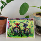 A greeting card featuring a colorful painting of a vintage bicycle parked in a field of flowers. Part of our Island Life series. 
