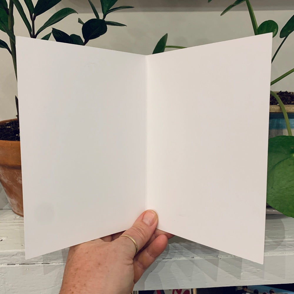 A greeting card from the Island Life series, being held open to show that it is blank inside.