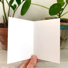 A greeting card decorated with chanterelle mushrooms, being held open to show that it's blank inside.