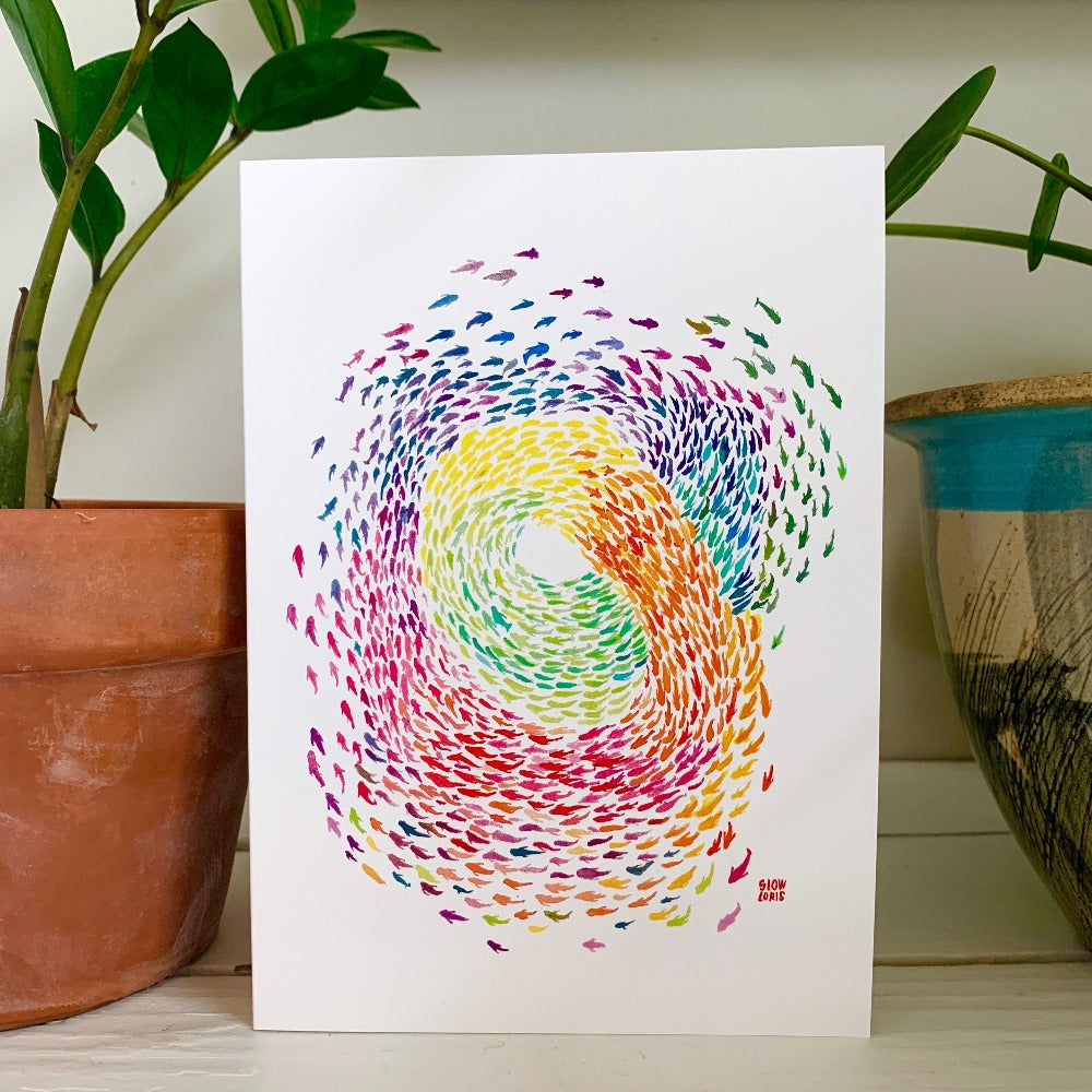 A greeting card printed with a rainbow-colored swirling school of fish.