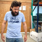Man with crazy hair, huge beard, and a weird look on his face while wearing a shirt with the helicopter van with tracks and skis on it.