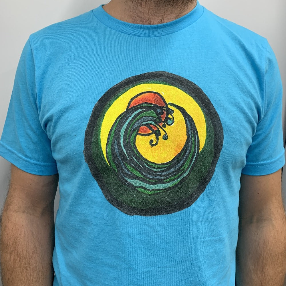 man wearing light blue t-shirt with a circle encompassing a wave and sun. Ink is yellow, orange, green and black