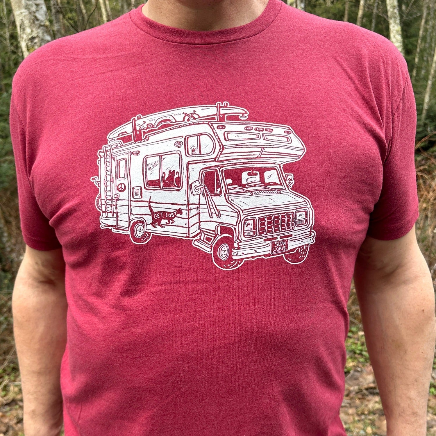 Man standing outside wearing a red shirt with a loaded up RV on it. .