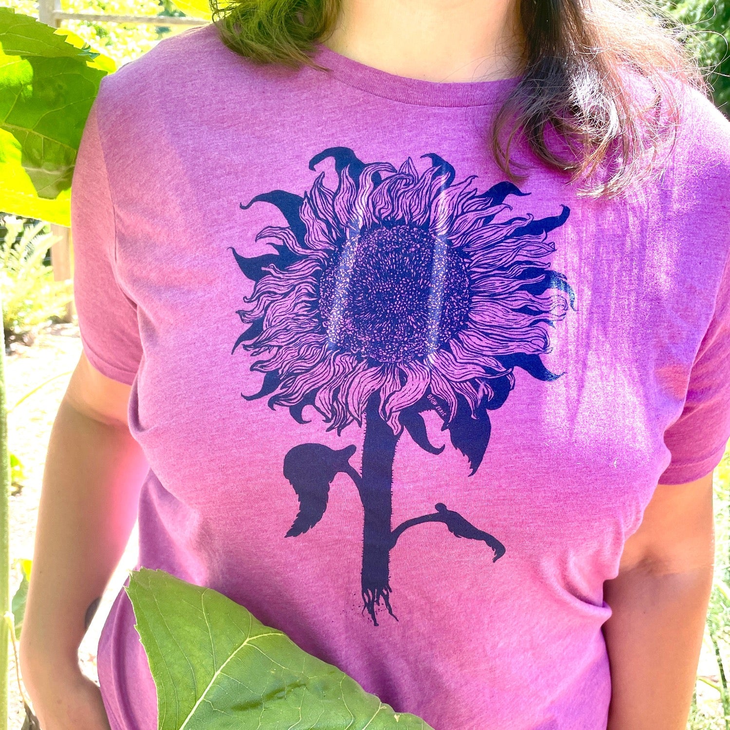 Woman wearing purple tinted pink shirt with a sunflower printed in 