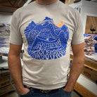 Night Ride print on tan shirt in dark blue ink. Mountain scene with raincloud, crescent moon, and bicyclist riding down the mountain
