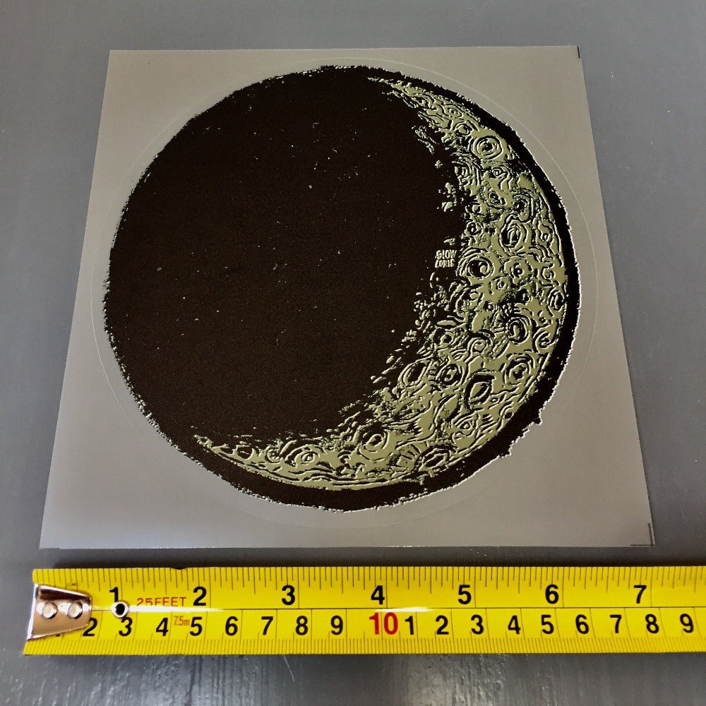 A large vinyl "stained glass" sticker in the shape of the waxing crescent moon. Under the sticker is a tape measure showing the size as 7 inches.