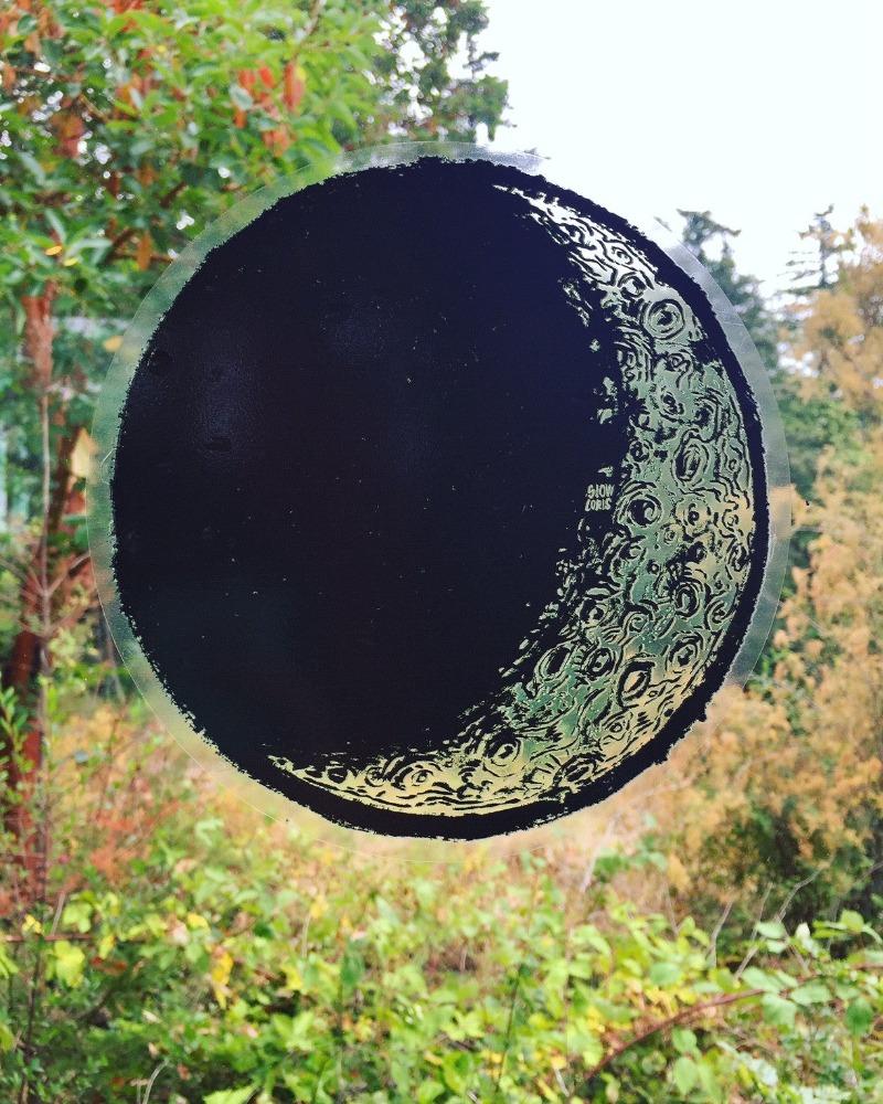 A large vinyl "stained glass" sticker in the shape of the waxing crescent moon, attached to a window.