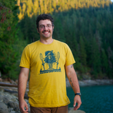 Smiling man standing outdoors, wearing a t shirt printed with a tree dude standing in a canoe.
