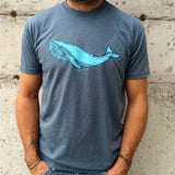 Blue t shirt printed with a whale in two colors, modeled by man in jeans.